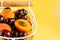 Apricots and cherries close up white metal basket, bright yellow background