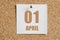 April 01. 01th day of the month, calendar date. White calendar sheet attached to brown cork board. Spring month, the concept of