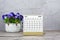 April 2023 desk calendar on wooden desk with potted plant.