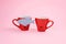 April Fools \' Day celebration, paper fish prank. Two joking laughing coffee cups with paper fish on pink background. All Fools \' D