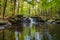 Apshawa Falls in a suburban nature preserve in NJ is surrounded by lush green forest on a summer afternoon