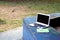 Aptop computer, eyeglasses, notebook and pen at an outdoor park