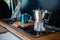 Aqua Bialetti stovetop coffee maker and mug, on a van gas cooker