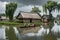 Aquatic Challenge: Village Submerged in Floodwaters - Thatched Roof Cottages Half-Covered, Villagers Navigating in Makeshift Boats