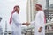 Arab Businessman Muslim dress shaking hands together in modern city UAE background. Muslim Men Teamwork business partner handshake