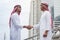 Arab Businessman Muslim dress shaking hands together in modern city UAE background. Muslim Men Teamwork business partner handshake