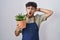 Arab man with beard holding green plant pot crazy and scared with hands on head, afraid and surprised of shock with open mouth