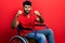 Arab man with beard sitting on wheelchair angry and mad raising fists frustrated and furious while shouting with anger