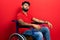 Arab man with beard sitting on wheelchair looking at the camera blowing a kiss on air being lovely and sexy