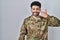 Arab man wearing camouflage army uniform pointing with hand finger to face and nose, smiling cheerful