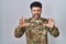 Arab man wearing camouflage army uniform smiling funny doing claw gesture as cat, aggressive and sexy expression