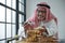 Arab senior man smiling and holding Brix Refractometer and glass plate contain piece of date palm slices for test sweetness