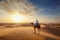 An Arab sits on a camel and looks at the sunrise. An Arab herdsman sits in the desert looking to the west