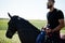 Arab tall beard man wear in black and sunglasses ride arabian horse