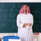 Arab teacher in front of chalkboard