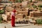 Arab woman dressed in red looks at the mobil in the Kasbah Ait Ben Haddou in Ouarzazate, Morocco October 2019