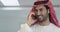 Arabian businessman wearing traditional clothes while using smartphone at home