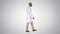 Arabian doctor in white robe walking on gradient background.