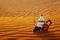 Arabian teapot, cup and dates in the desert at a beautiful sunset