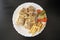 Arabic chicken shawarma plate with fried fries and pickled vegetables on dark wooden background, top view. Shawarma wrap on white