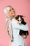 Arabic girl in hijab holding cute corgi puppy, isolated on pink