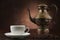 Arabic kettle with cup of coffee on brown background