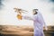 Arabic man with traditional emirates clothes walking in the desert with his falcon bird