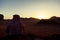 An arabic man wearing Jordanian keffiyeh head wrap is sitting on top of a rock overlooking the Wadi Rum Desert i