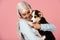 Arabic woman in hijab holding cute corgi puppy, isolated on pink