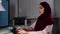 Arabic woman in hijab looks at monitor at office typing with the hands on computer keyboard.