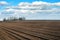 arable field of agricultural field while preparing land for sowing, with cloudly blue sky at spring