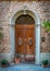 Arc entrance with old door to Tuscan house, Italy