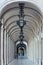 Arcade with vaulted ceiling and iron lamps in the building at Praca do Comercio in Lisbon, Portugal