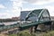 Arch bridge with car traffic crossing river.  Metal arch Victorian construction