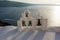 Arch with cross and bells of traditional Greek white church in Oia village, Santorini Island, Greece