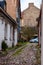 Arch gates to medieval paving stone grungy but stylish and cozy end street with parked car in Old Town of Vilnius. Classical