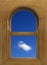 Arch shaped wood window frame with white cloud in blue sky