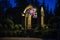 An arch with stained glass windows stands in a green blooming park