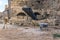 Archaeological site among ancient ruins with a conveyor for stones, theodolite and wheelbarrow in the foreground