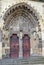 Arched  antique wooden door  with  black iron ornaments in a stone wall. Basilica Minor of Saint Benedict in Hronsky Benadik