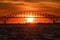 Arched bridge silhouette in front of large setting sun