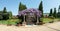 Arched constructionr covered with colorful lilac purple drooping wisteria flowers over a stairs pathway leading to a house