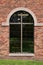 Arched glass window on brown brick wall