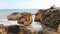 Arched primitive stone bridge at student beach in Lagos, Algarve, Portugal - Low angle Fly-Over Aerial