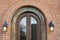 Arched window on a red brick building wall with lantern lamps on the side