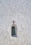 Arched window in a white-stone brick wall with an openwork arch in the form of a cross, background