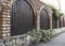 Arched wood planks, brick and stone fence with foliage