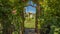 Arched wooden arbor at the entrance of a garden with playhouse slides and swings