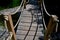 Arched wooden bridge in the park. the railing posts are connected by a strong jute rope. Knots finished with a rope work of a Japa