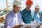 Architect And Builders Looking At Buiding Plan Blueprint Wearing Hardhat While Meeting On Construction Site